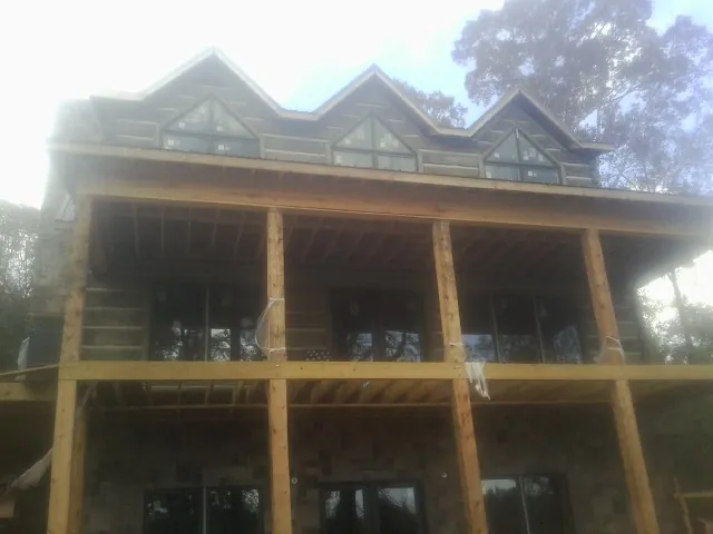 Dormers and porch framing on a large log home under construction — Roof Coating work by our crew in Garrett
